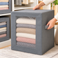 Grey fabric storage box with a clear window holding folded sweaters, a hand on the side handle